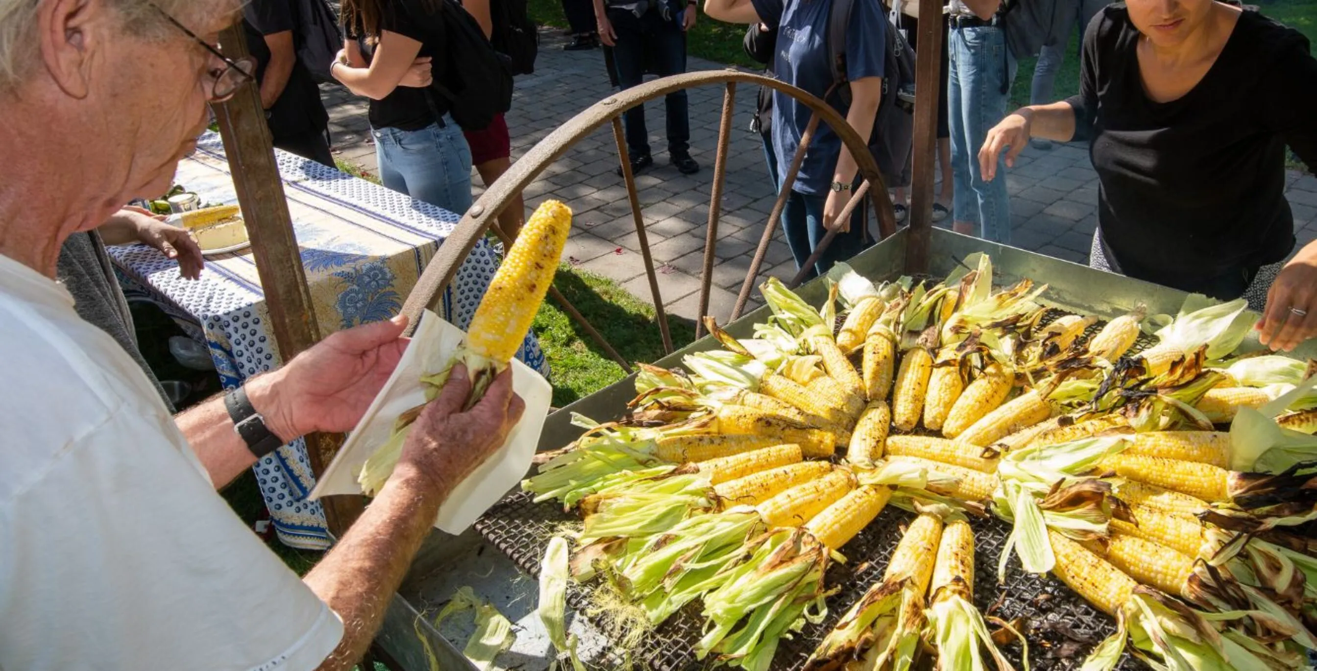a man serves freshly roasted corn to a crowd of community members