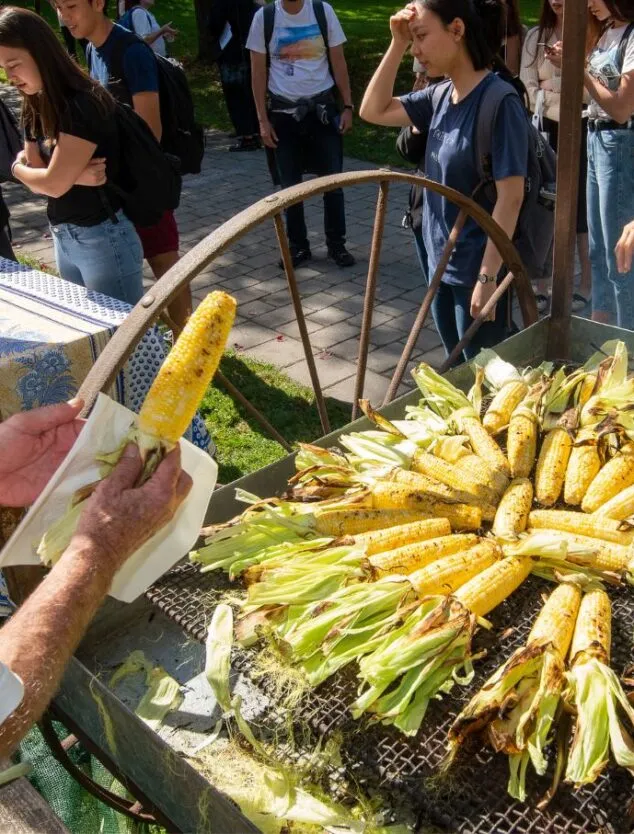 a man serves freshly roasted corn to a crowd of community members