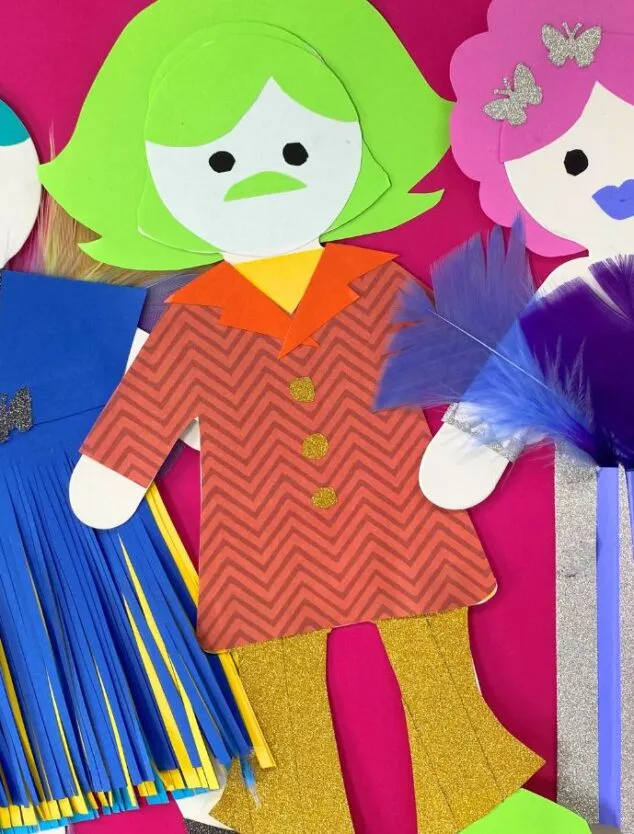 Three vibrant dolls are adorned with paper clothing. Additional details and texture are created with glitter, tape, feathers and pleats.