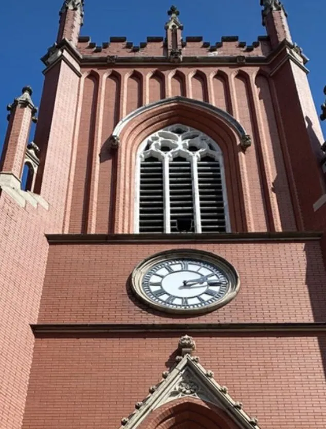 an image of the exterior of a cathedral, captured from below. A blue sky with some clouds appears in the background.